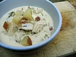 A bowl of fish chowder, with tilapia, red potato, chopped dill, and other ingredients