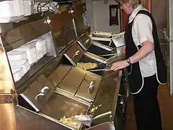 Two parcels of pastry being lowered in a basket into oil