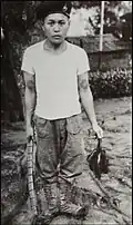 An Iban headhunter posing with a human scalp