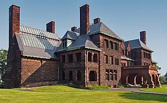 A reddish-brown three-story stone mansion with several chimneys